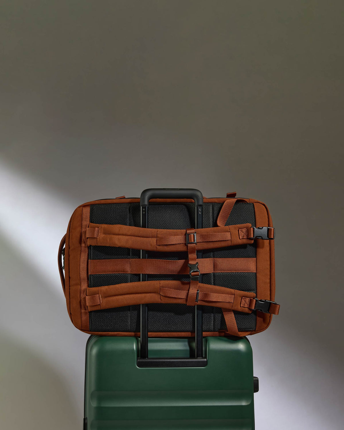 a brown and black bag on top of a green suitcase