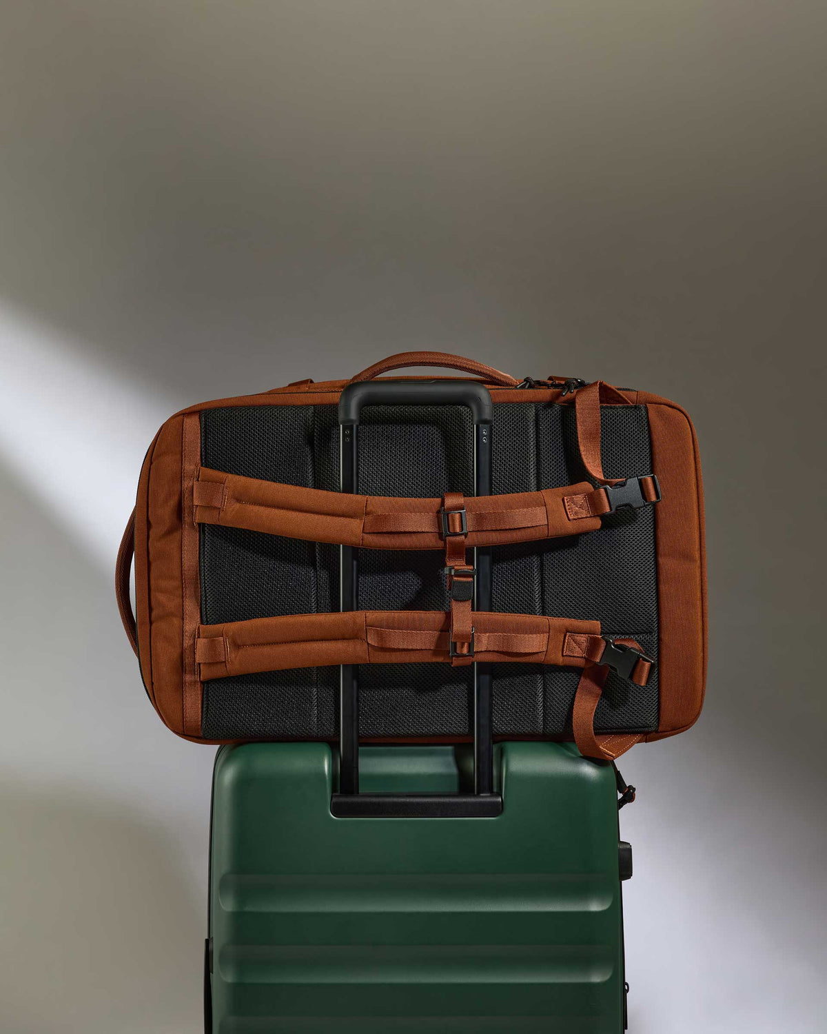a brown and black bag on top of a green suitcase