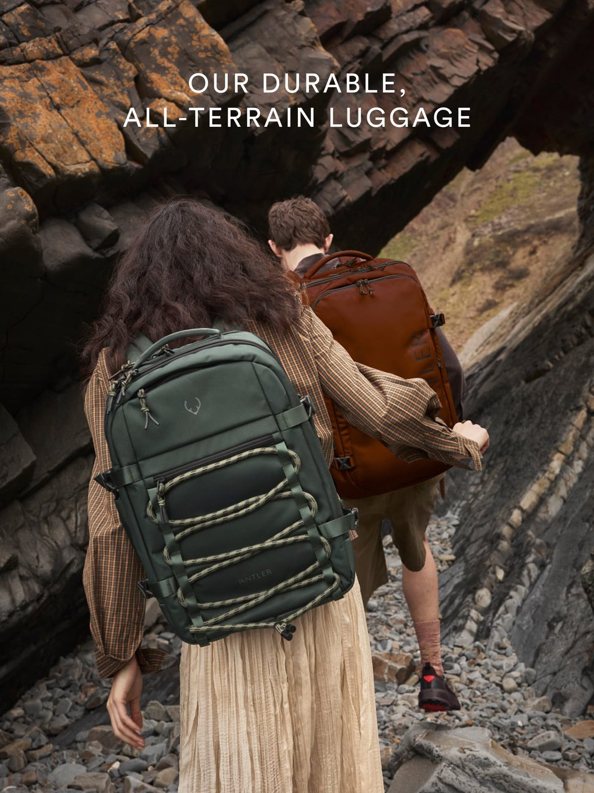 a man and woman with backpacks walking up a rocky cliff