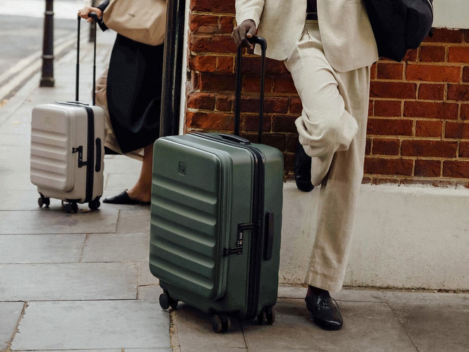 a person in a suit leaning against a wall with luggage