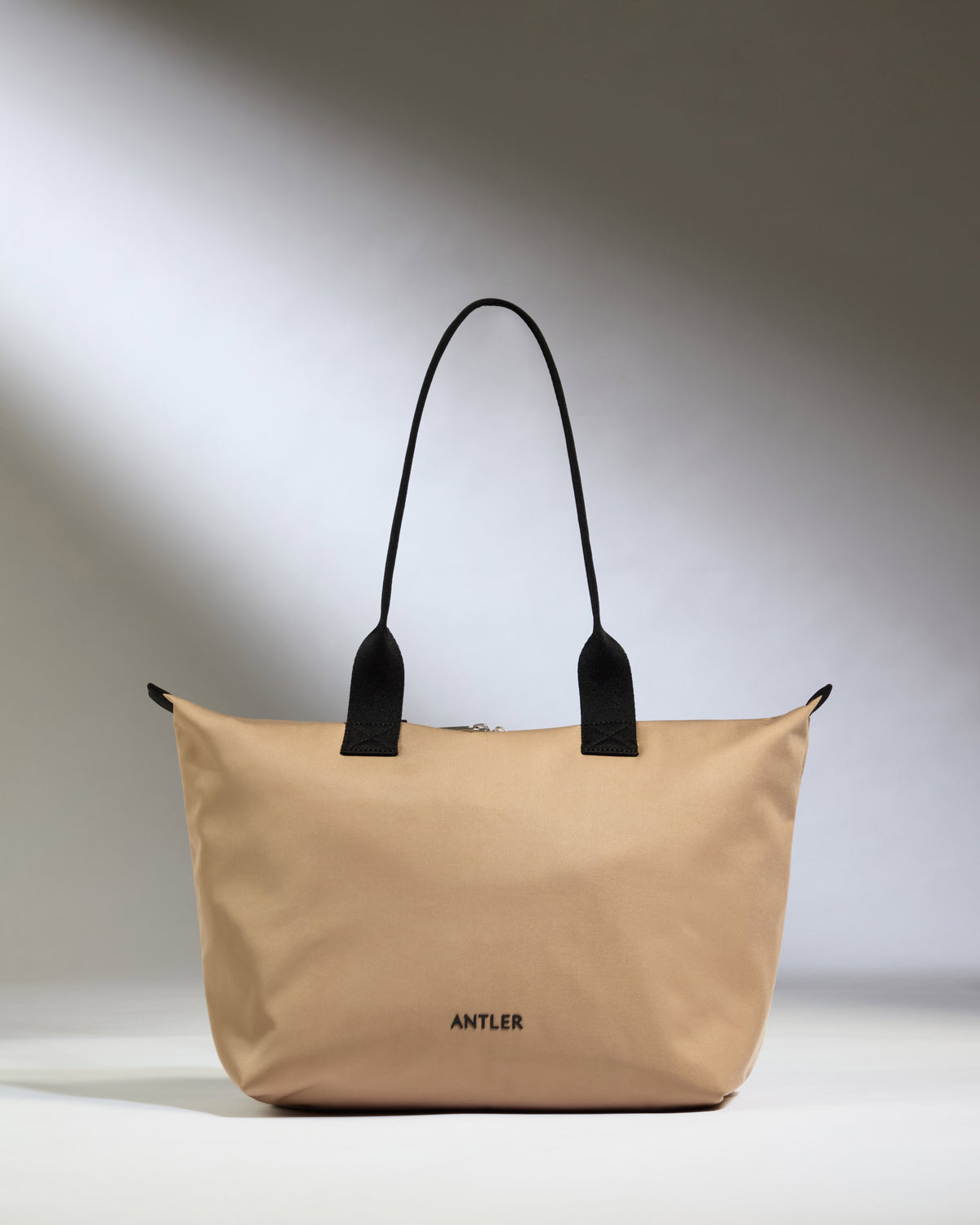 a tan bag with black handles