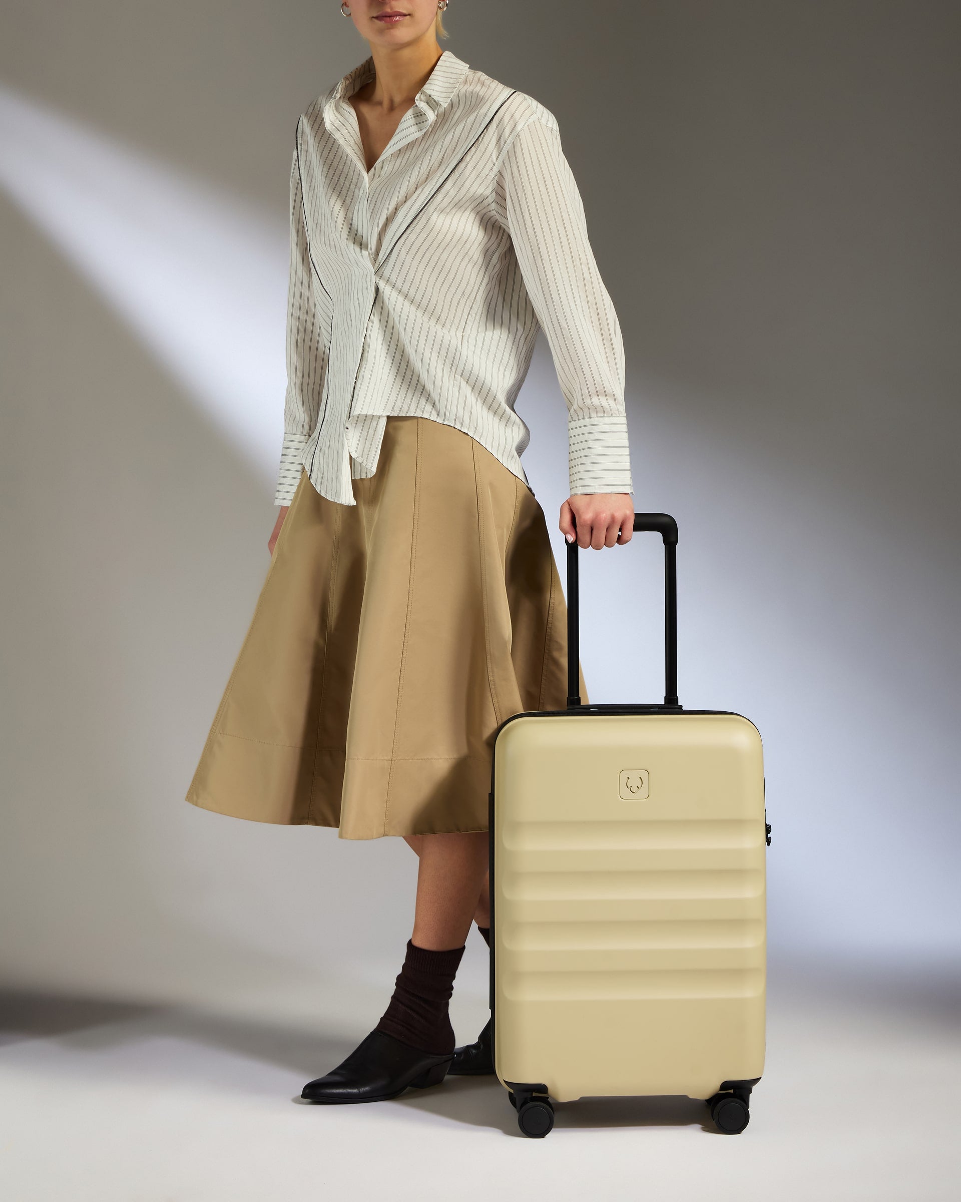 a woman in a skirt and a white shirt holding a suitcase