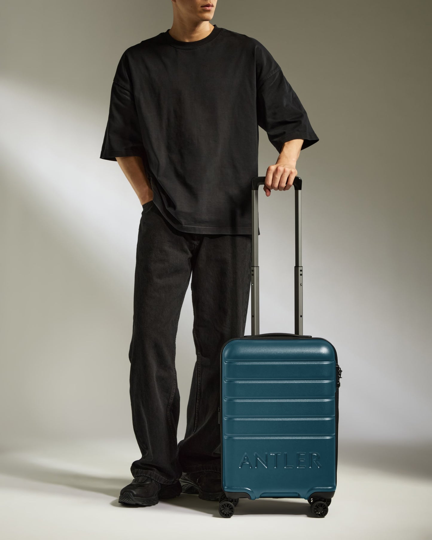 a man standing with his hands in his pockets and a suitcase
