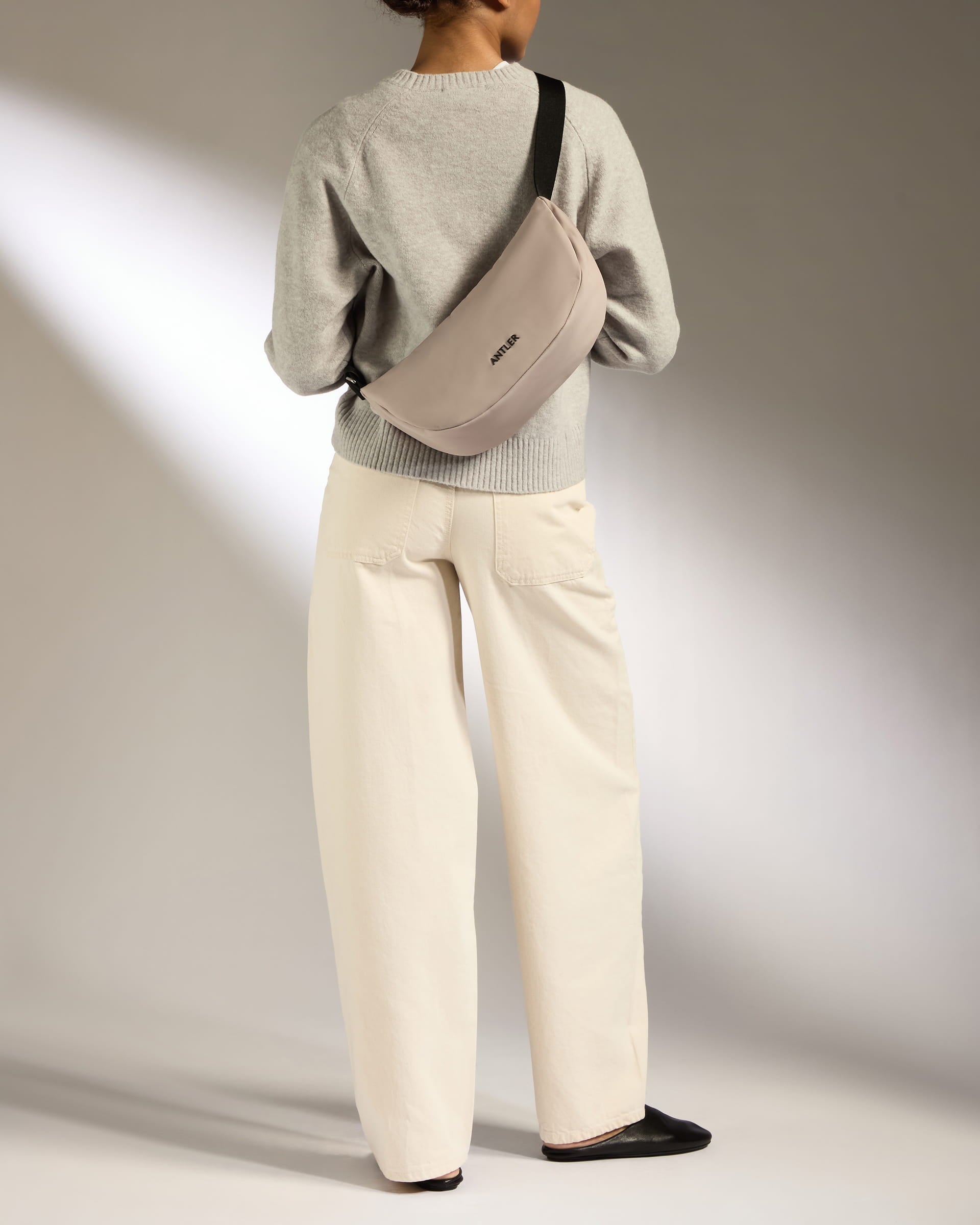 a woman wearing a grey sweater and white pants