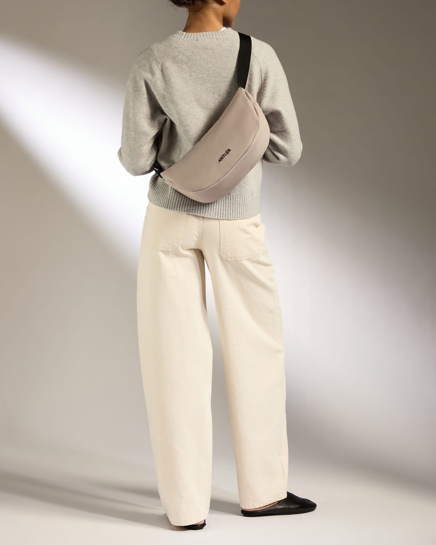 a woman wearing a grey sweater and white pants