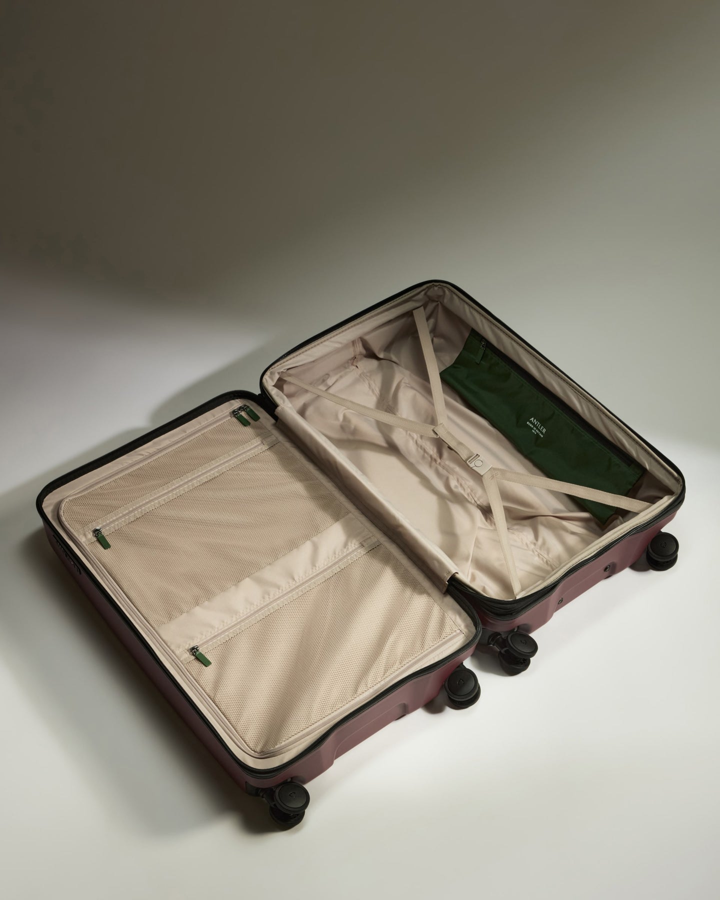 a suitcase with wheels and a green bag