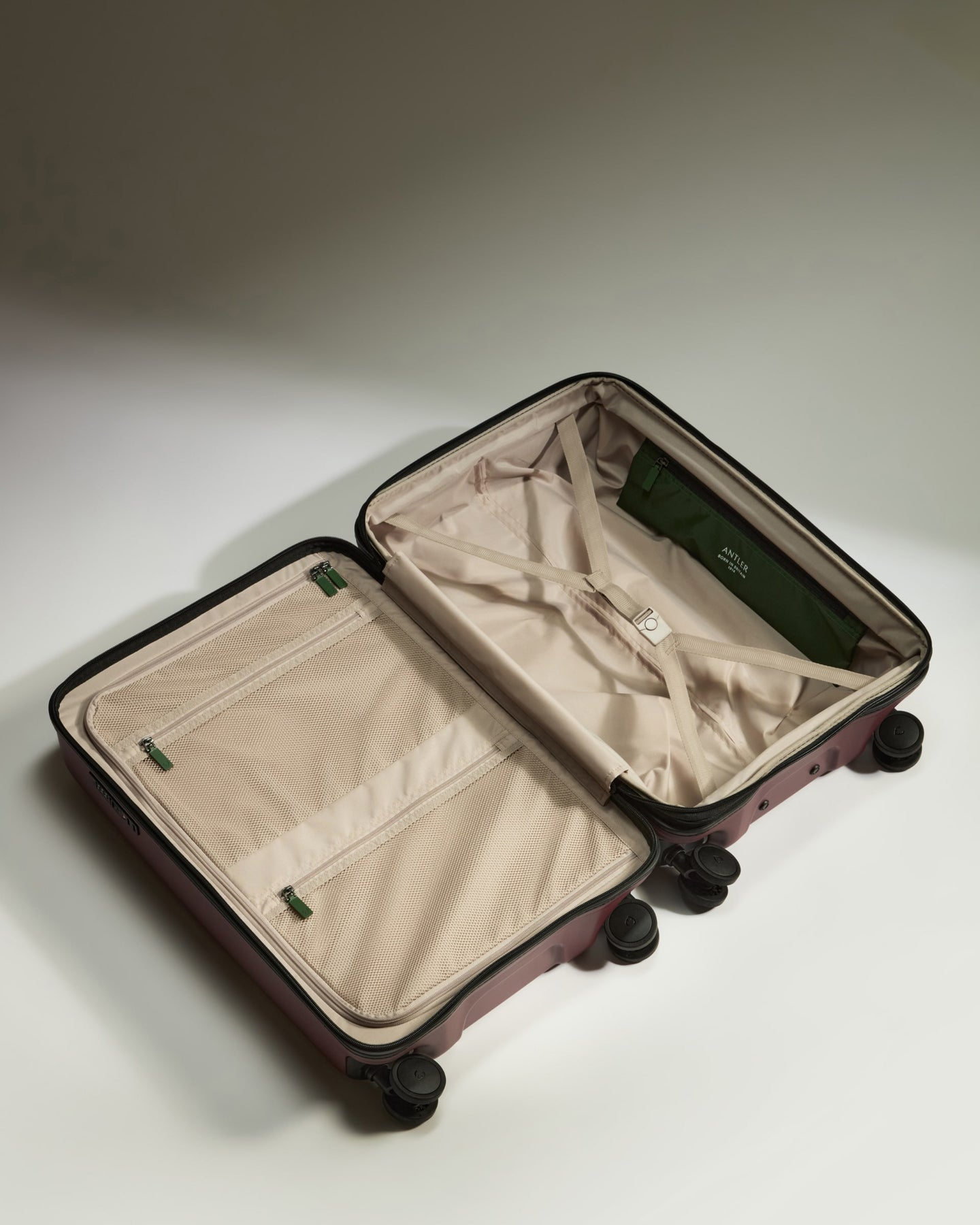 a suitcase with wheels and a green bag