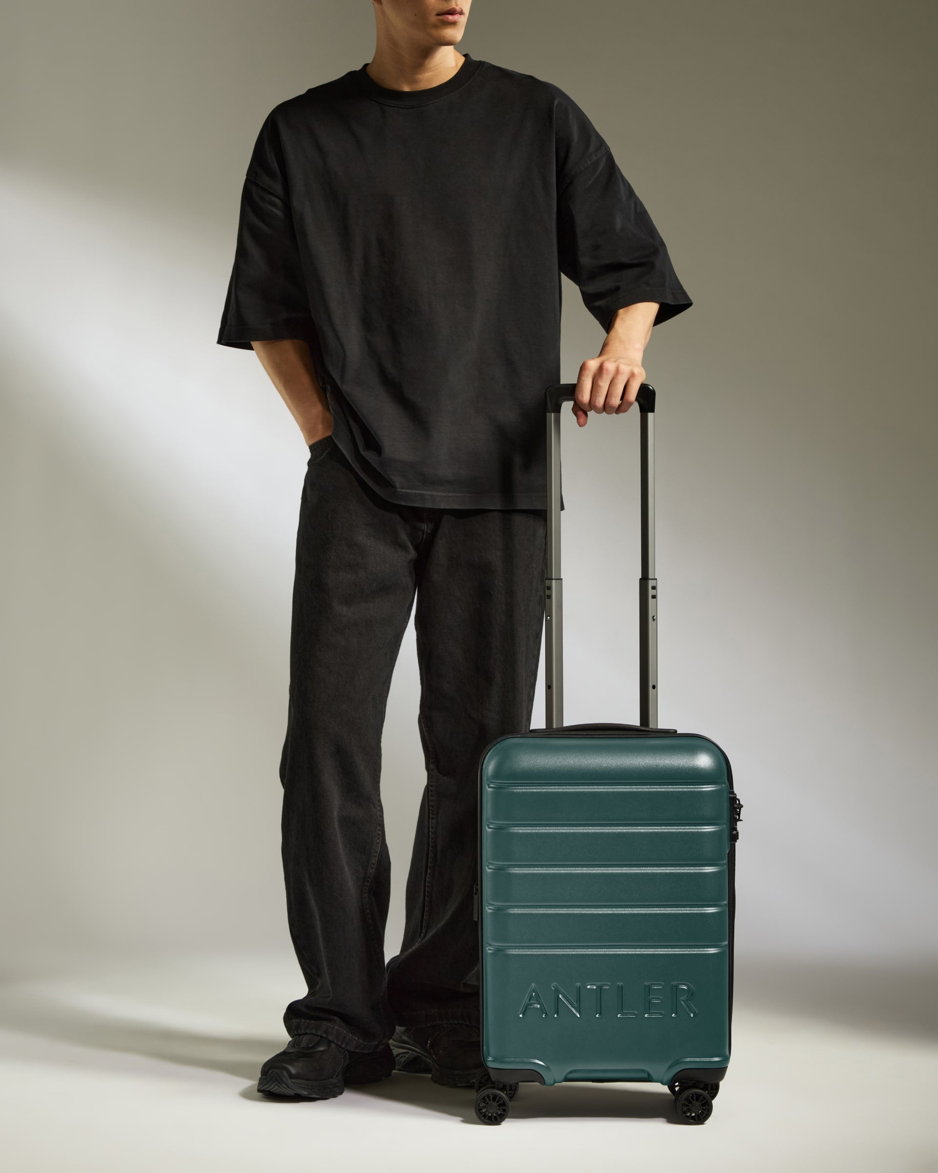 a man standing with his hands in his pockets and a suitcase