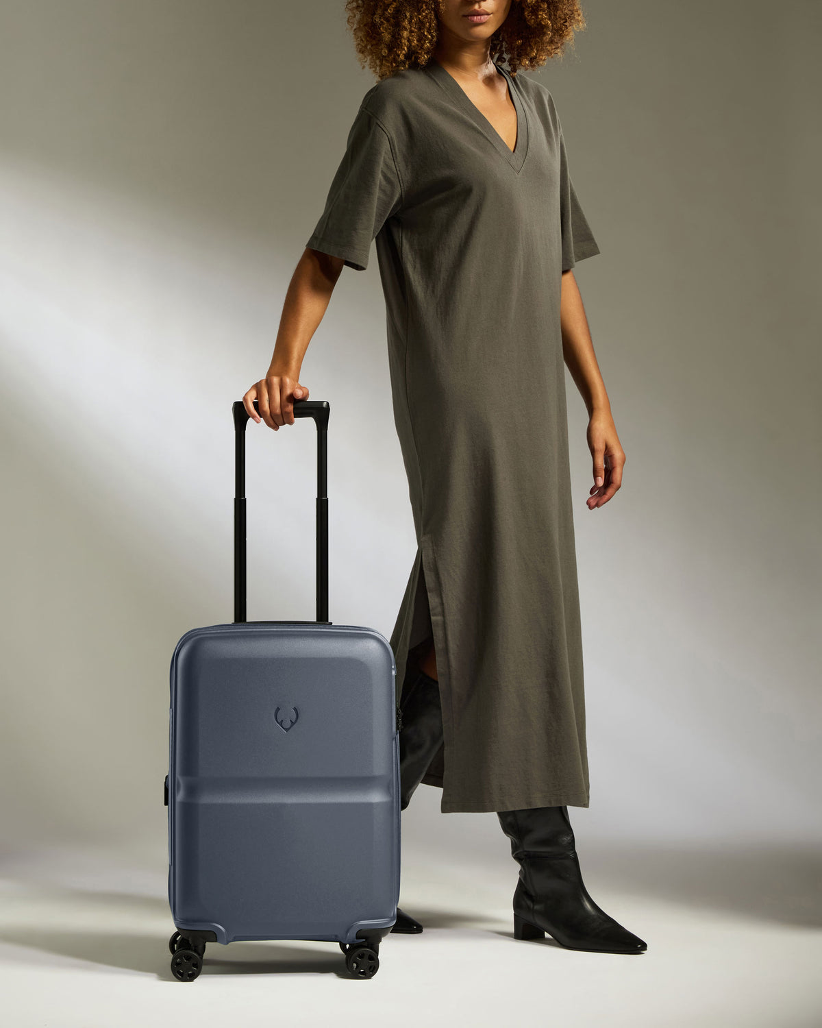 a woman in a long dress and boots holding a suitcase