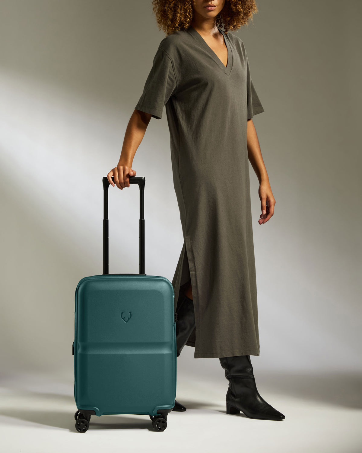 a woman in a long dress and boots holding a suitcase