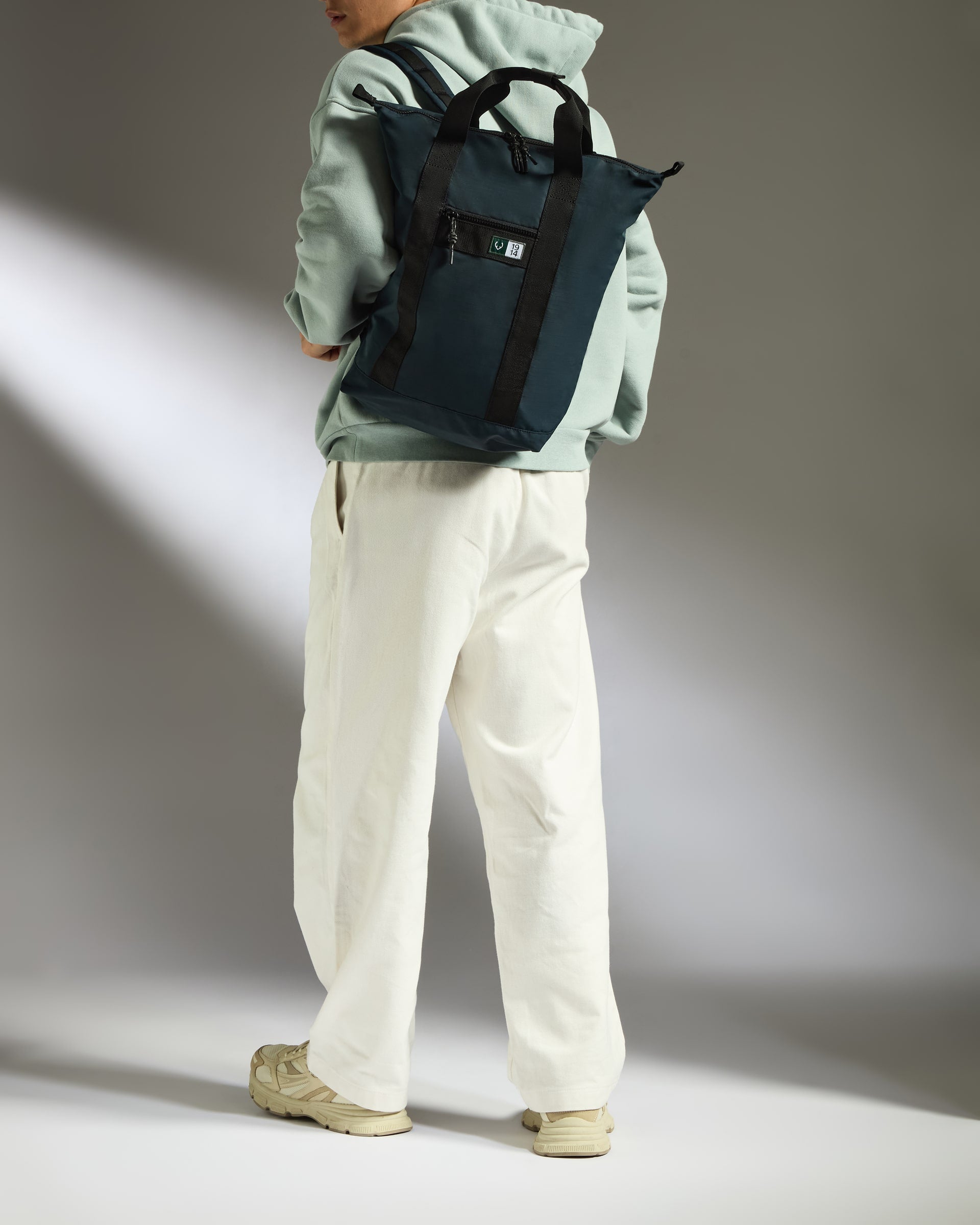 a person wearing a green sweatshirt and white pants