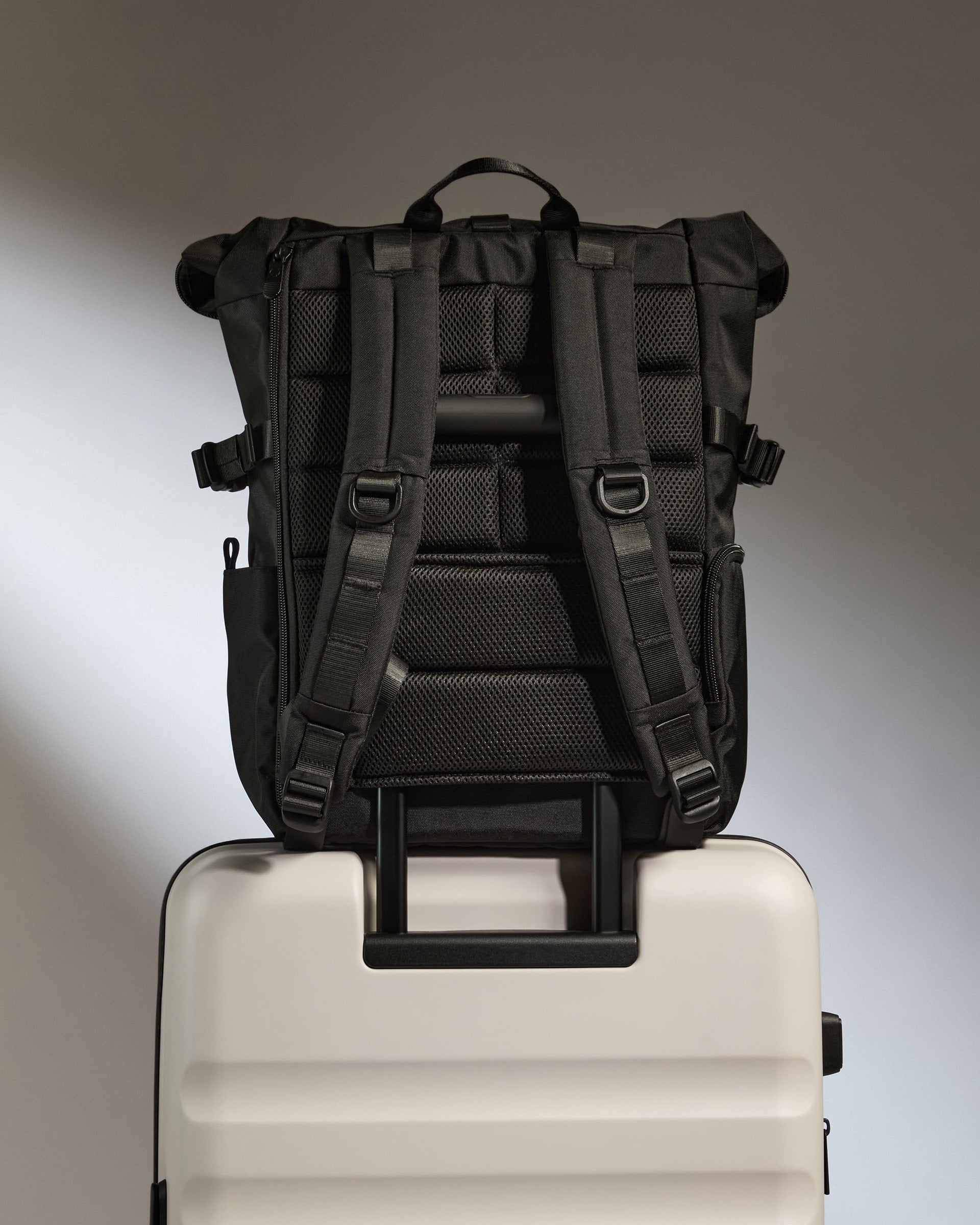 a black backpack on top of a white suitcase