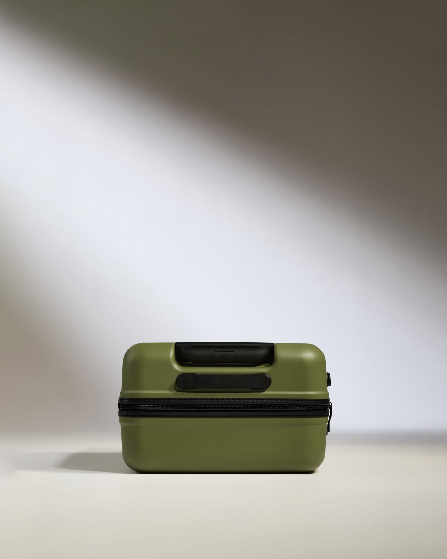 a green suitcase on a white surface