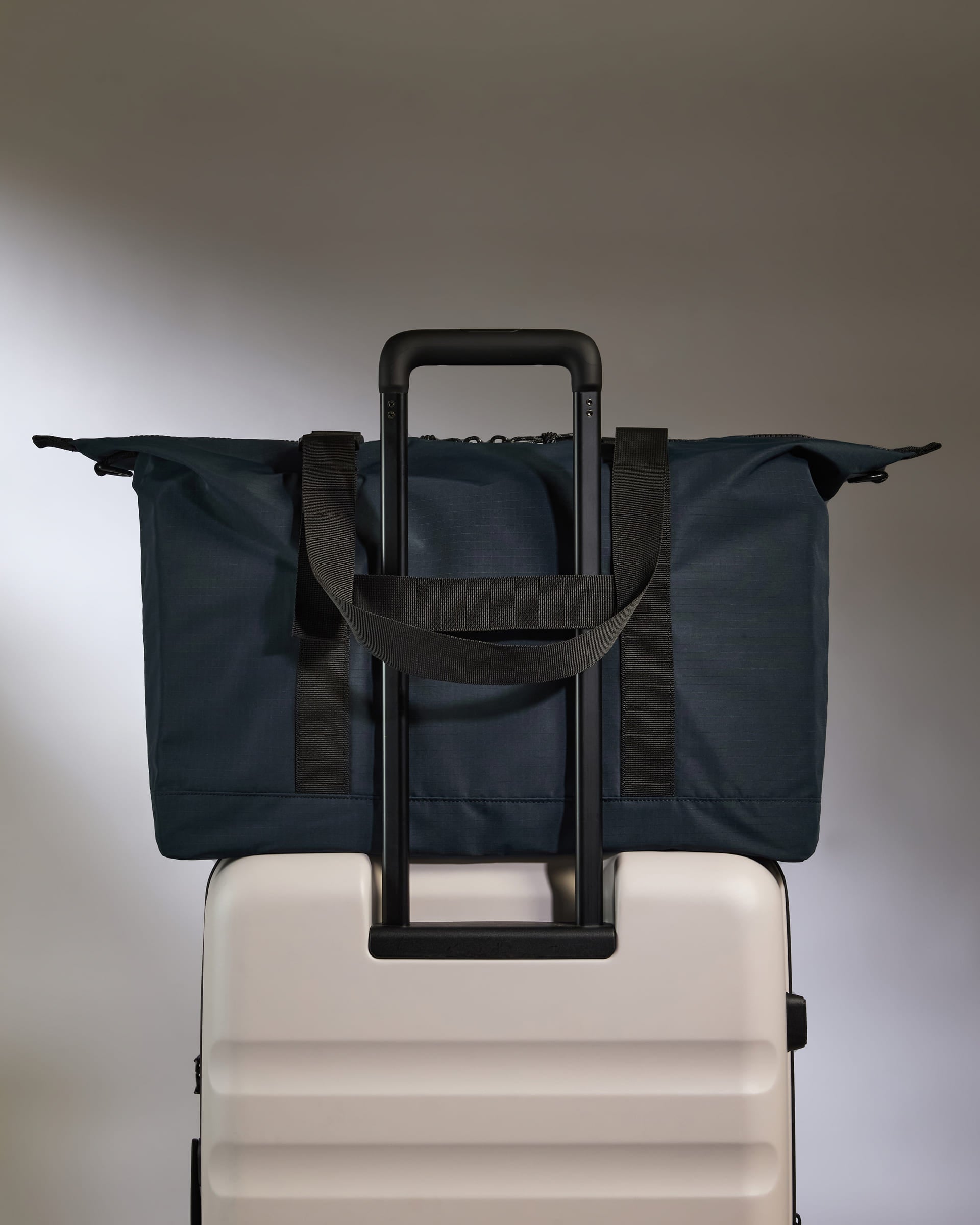 a blue bag on top of a white suitcase