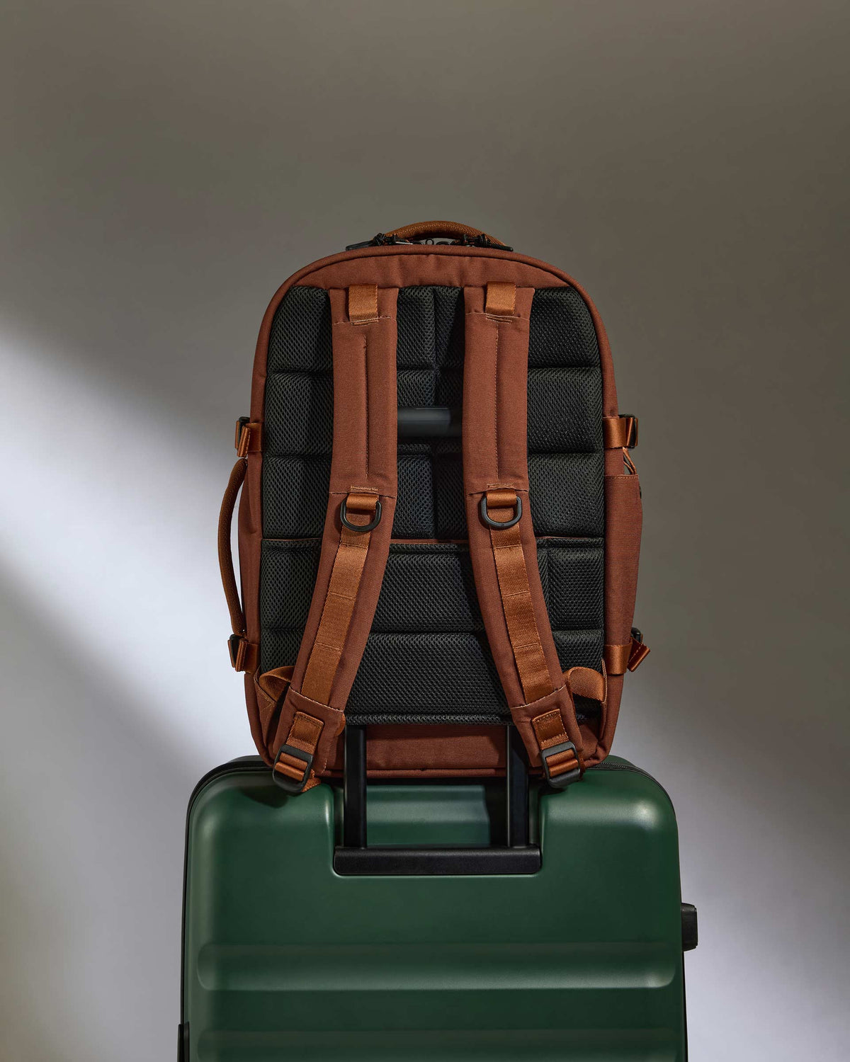 a backpack on top of a green suitcase