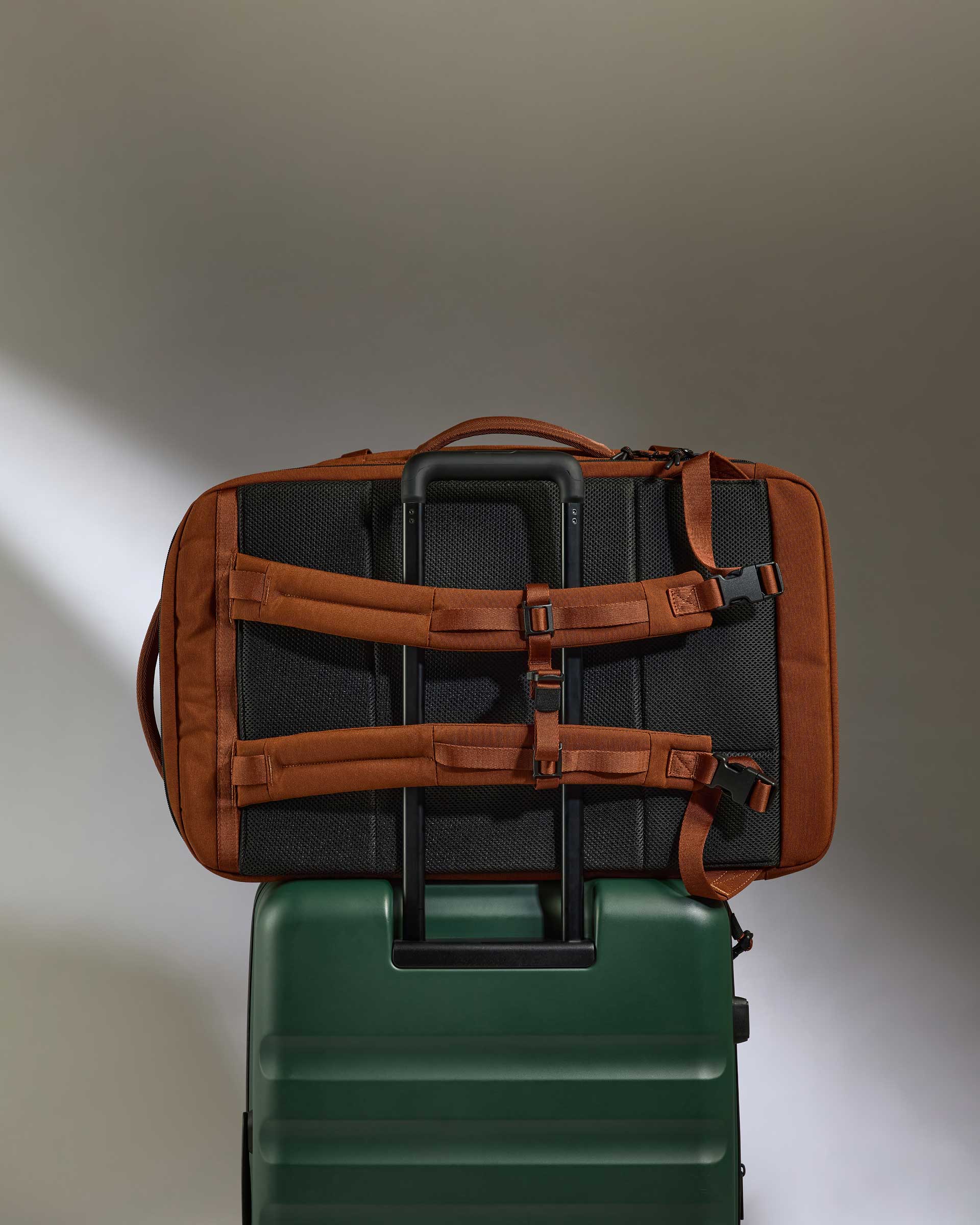 a brown and black bag on top of a green suitcase