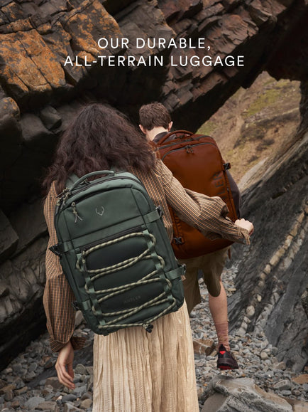 a man and woman with backpacks walking up a rocky cliff