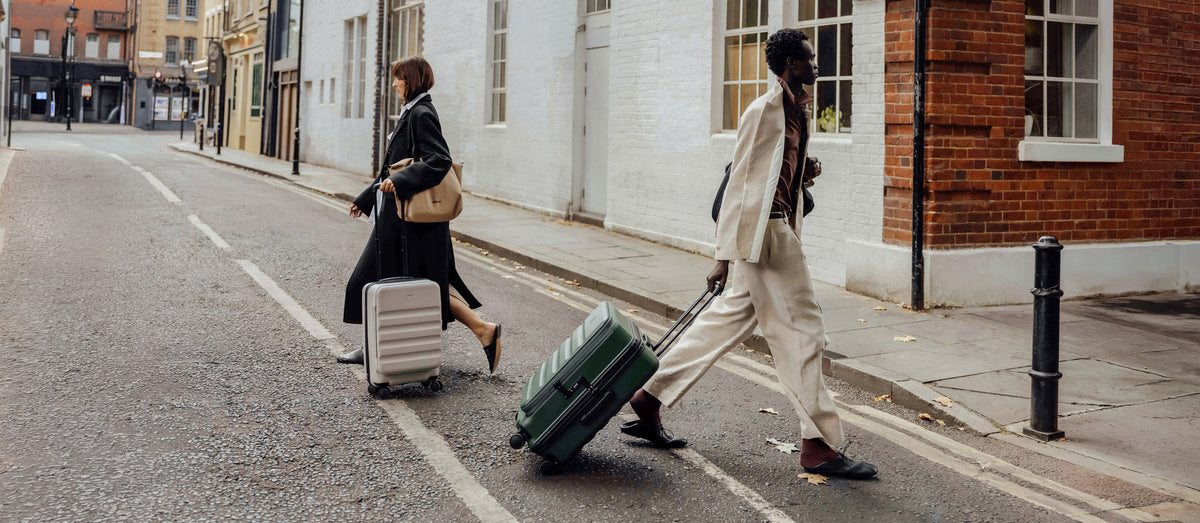 a man and woman walking with luggage on the street