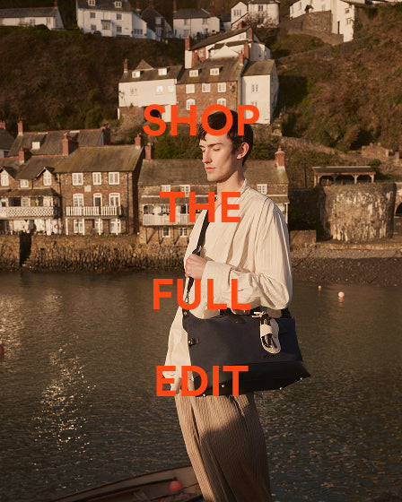 a man standing in front of a body of water with a bag