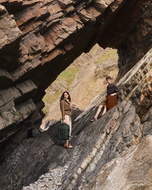 a man and woman standing on a rock with luggage